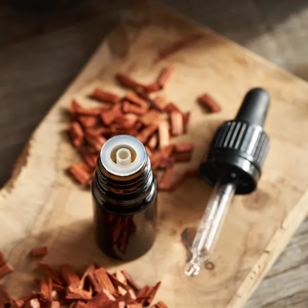 Une bouteille d'huile essentielle et des copeaux de bois rouge pour le drainage lymphatique.
